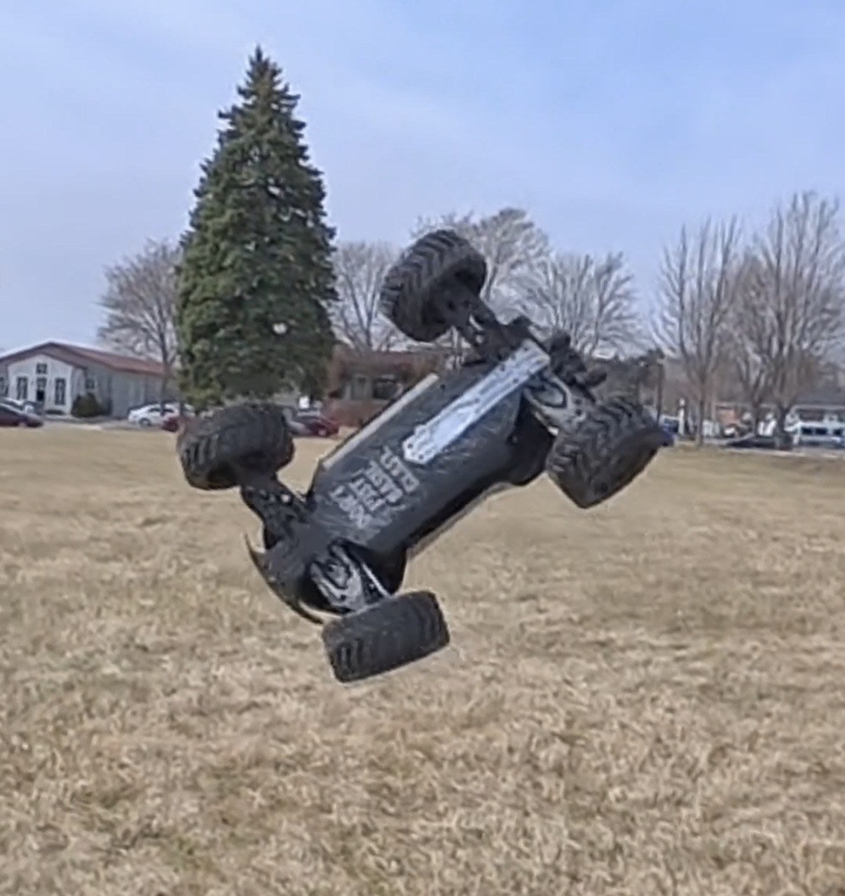 RC monster truck airborne and inverted over a grass field